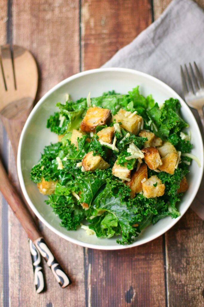 Kale Salad with Gruyere and Garlic Croutons Overhead Shot in Large White Bowl